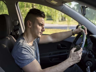 Man texting in car and holding beer bottle